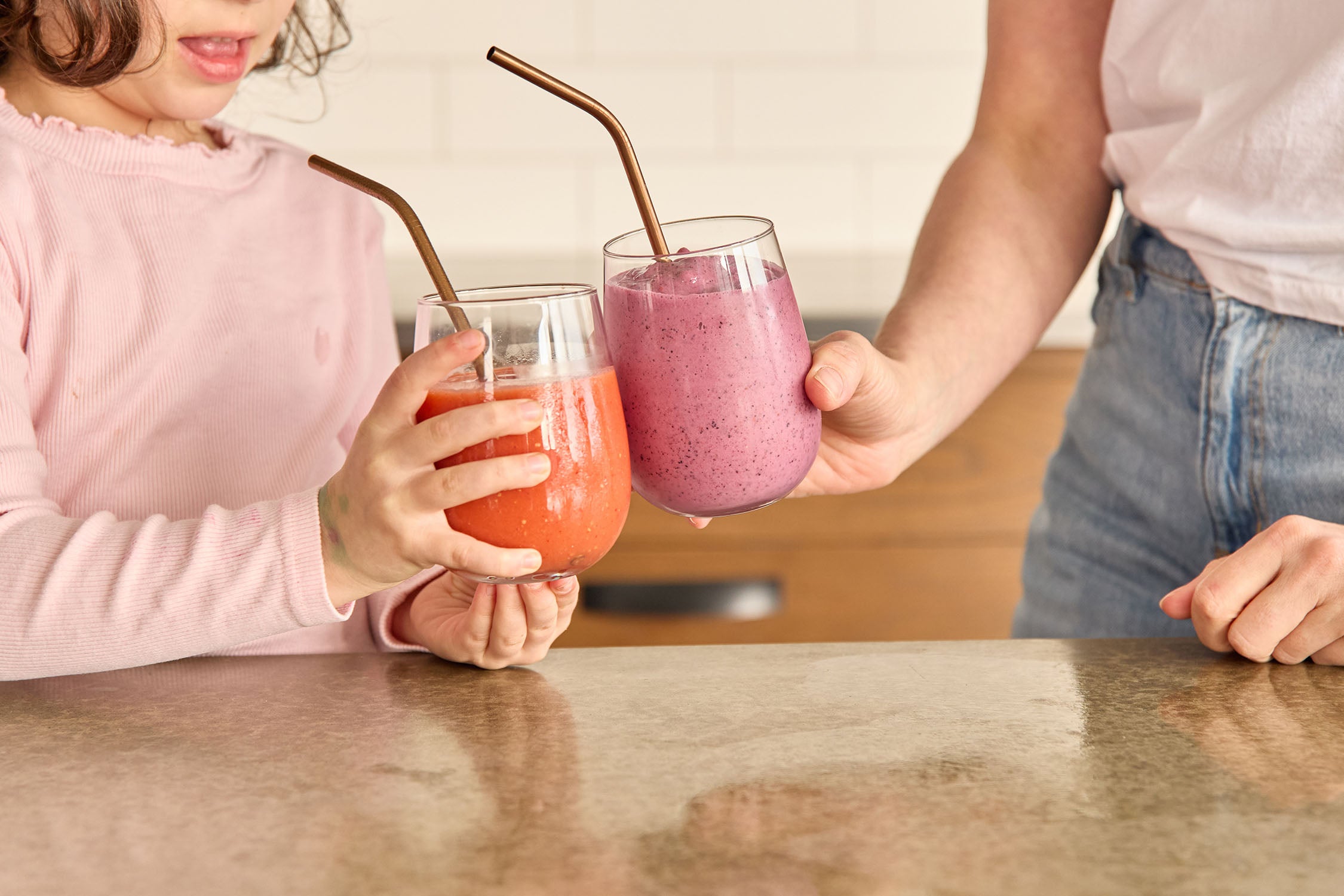 Mother daughter cheers healthy smoothies in glasses at home